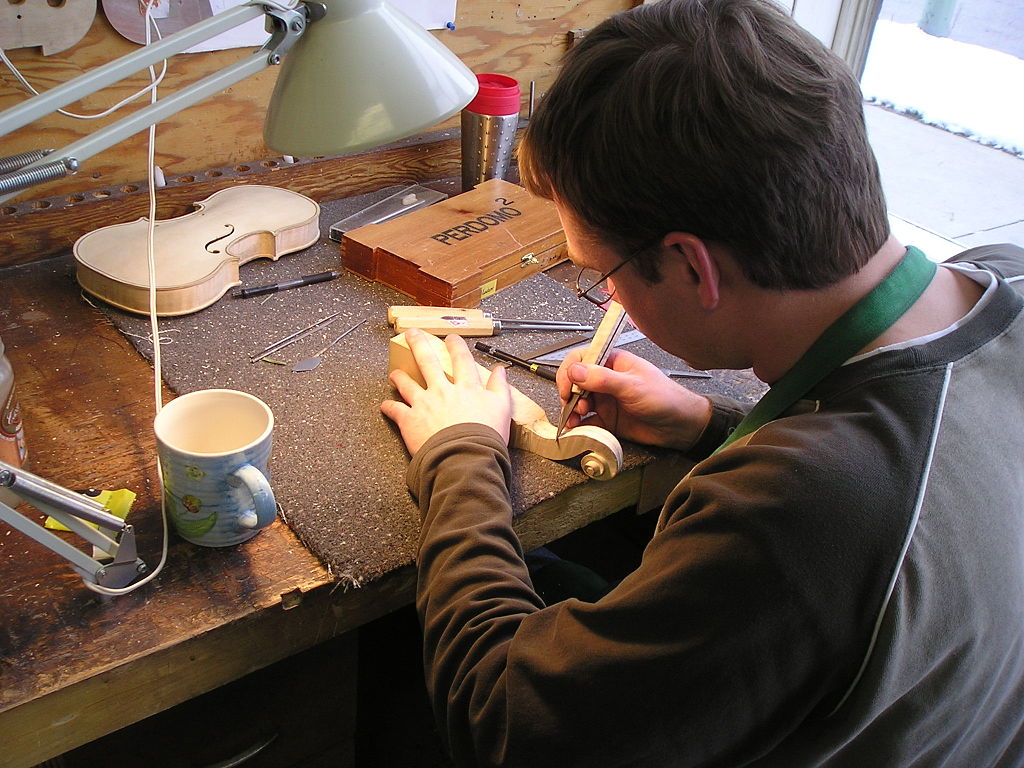 A luthier making a violin scroll and finger board