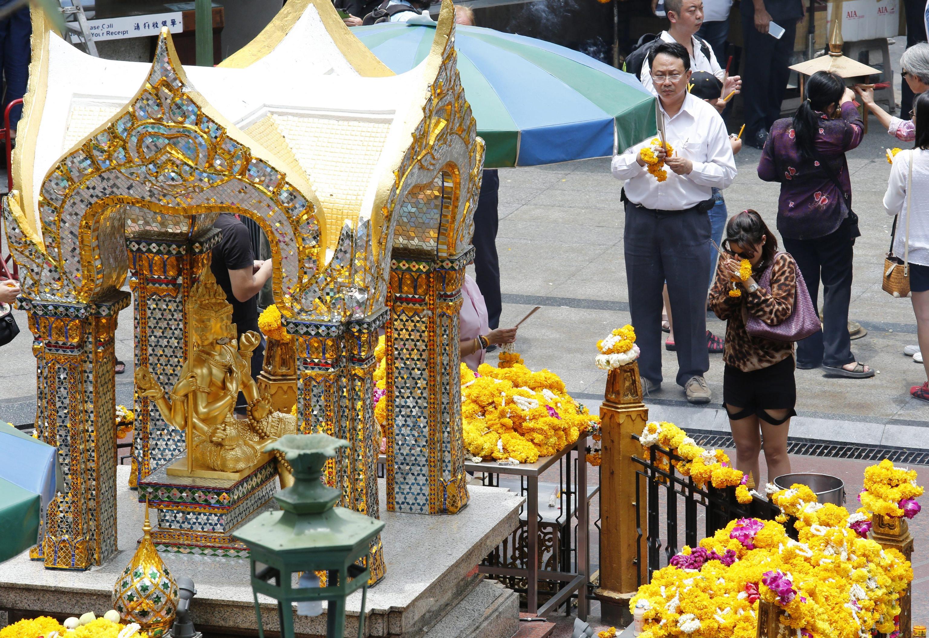 A woman prays before the site of a deadly bomb attack at the sacred Erawan Shrine