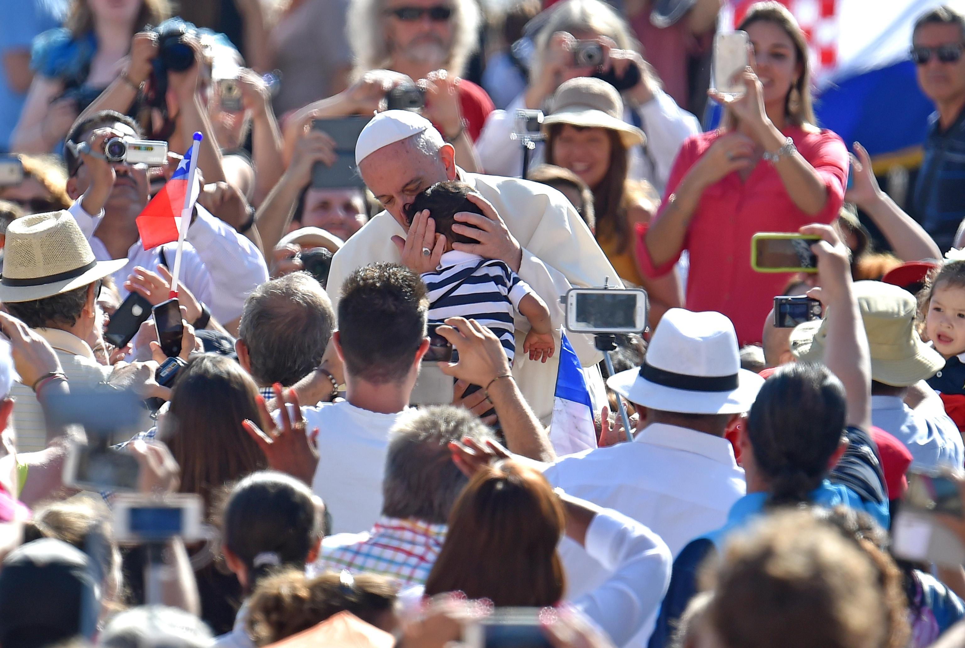 Pope Francis hugs a child arriving in St. Peter's Square for his weekly General Audience