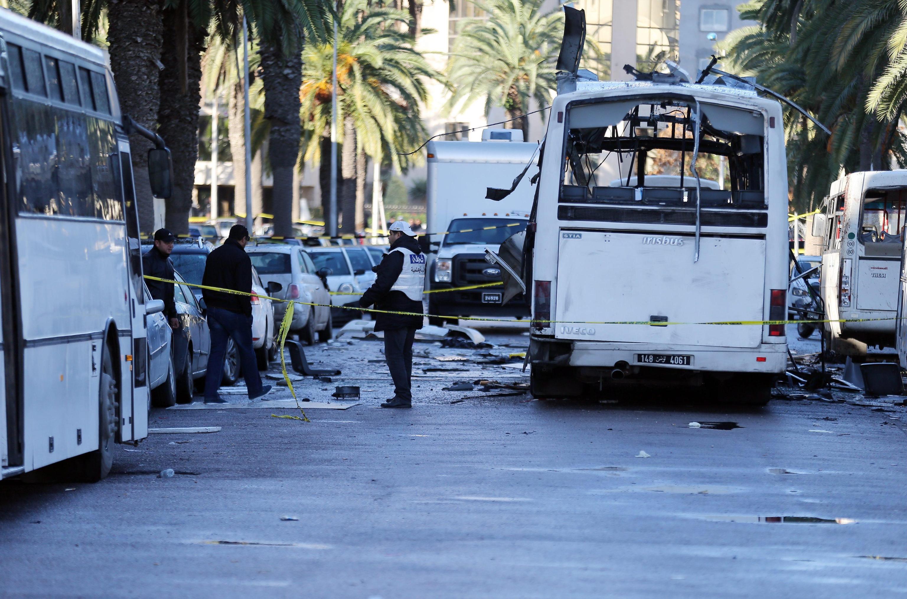 Tunisian forensic police inspect the wreckage of a bus in the aftermath of a bomb attack on a bus transporting Tunisia's presidential guard in Tunis