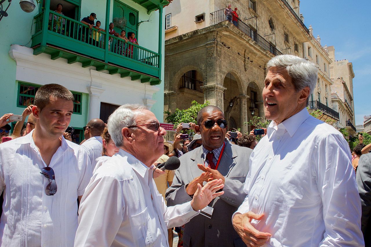 Cuban nationals watch as U.S. Secretary of State John Kerry and a tour guide walk through the Plaza de San Francisco in Old Havana during the Secretary's historic trip to Havana